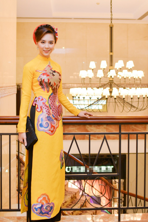 Vòng eo thon thả của bà mẹ hai con được tôn một cách khéo léo trong bộ áo dài vàng tươi nổi bật hoa văn thêu rồng sắc nét của NTK Thuỷ Nguyễn.