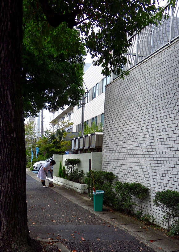 Một cô y tá ở Nhật đang quét dọn khu vực ngoài bệnh viện.