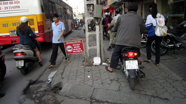 Người đi bộ bước xuống lòng đường phố Lê Duẩn để... nhường vỉa hè cho dòng xe máy đang hối hả di chuyển.