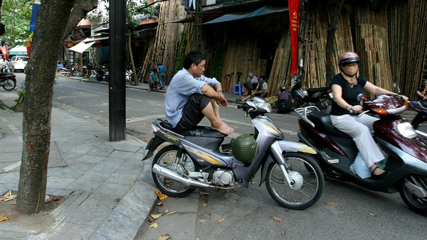 Điểm chờ khách của những người hành nghề xe ôm trên phố Hàng Vải nằm giữa lòng đường vì vỉa hè được ngầm mặc định thuộc sở hữu của các hộ kinh doanh.
