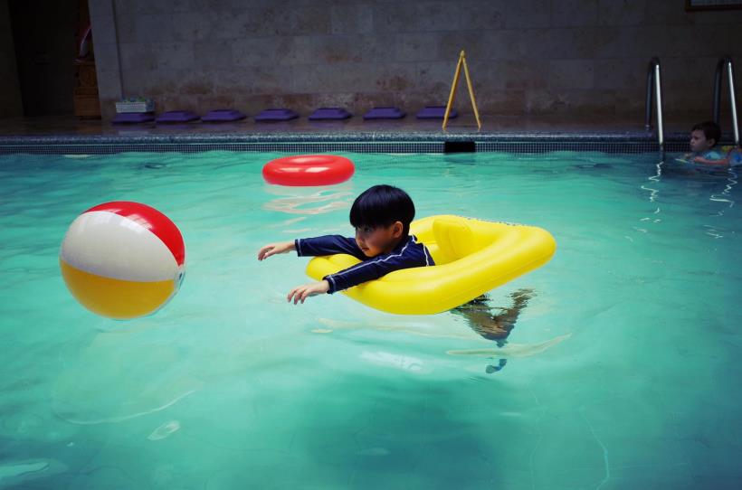 Cậu bé chơi đùa vui vẻ dưới bể bơi.