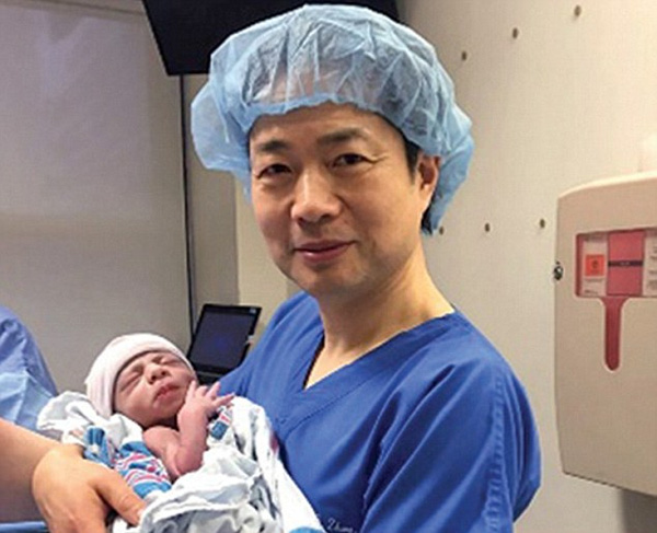 Bác sỹ Zhang, trưởng nhóm phôi học của thành phố New York, bế trên tay em bé đầu tiên của lịch sử sinh ra bởi 3 bố mẹ