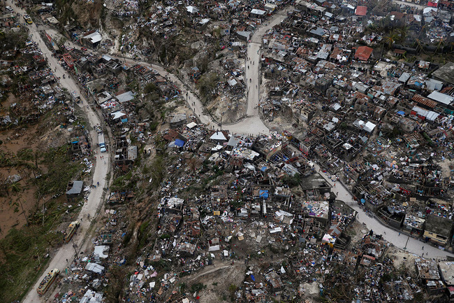 Người dân lang thang trên đường phố. Bên cạnh đó, những ngôi nhà bị phá hủy hoàn toàn tại Jeremie, Haiti.