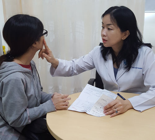 TS Lê Thái Vân Thanh đang khám cho một nữ bệnh nhân bị tác dụng phụ sau khi cấy phấn cho da. 