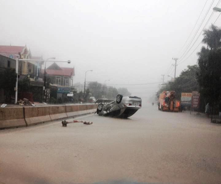 Một chiếc xe ô tô bị lật tại thành phố Đồng Hới (Quảng Bình) khi đi qua đoạn đường bị ngập do mưa lũ - (Ảnh: Thanh Niên).