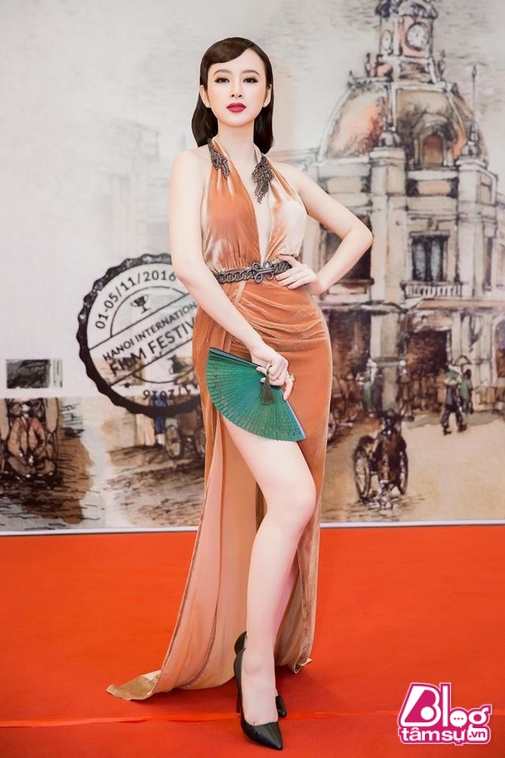 Angela Phương Trinh nhanh chóng thu hút sự chú ý trên thảm đỏ Liên hoan phim Quốc tế Hà Nội 2016 khi hóa quý cô cổ điển với kiểu tóc uốn nếp, diện bộ đầm xẻ cao màu gạch và tạo điểm nhấn khi cầm trên tay phụ kiện là 1 chiếc quạt.