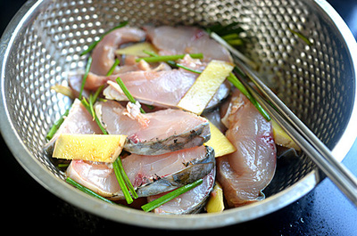 Cho cá vào thố, thêm rượu nầu ăn, nước tương, gừng, hành là và một ít muối trộn đều và ướp trong 15 phút. 
