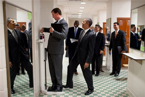 Ông đạp chân lên chiếc cân trong khi Giám đốc Nhà Trắng Marvin Nicholson đang đo thử cân nặng của mình trong phòng thay đồ dành cho các vận động viên bóng chuyền tại Đại học Texas