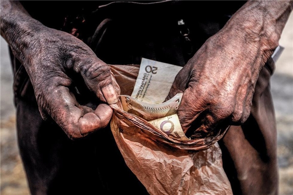 Công nhân bỏ tiền vào túi ni lông cẩn thận để bảo quản đồng lương ít ỏi của mình khỏi ẫm ướt