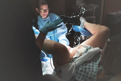 Bức ảnh của nhiếp ảnh gia Liz Jennings ghi lại cảnh chính bác sĩ cũng ngạc nhiên đến ngỡ ngàng trong giây phút nước ối của sản phụ bắn lên. 
